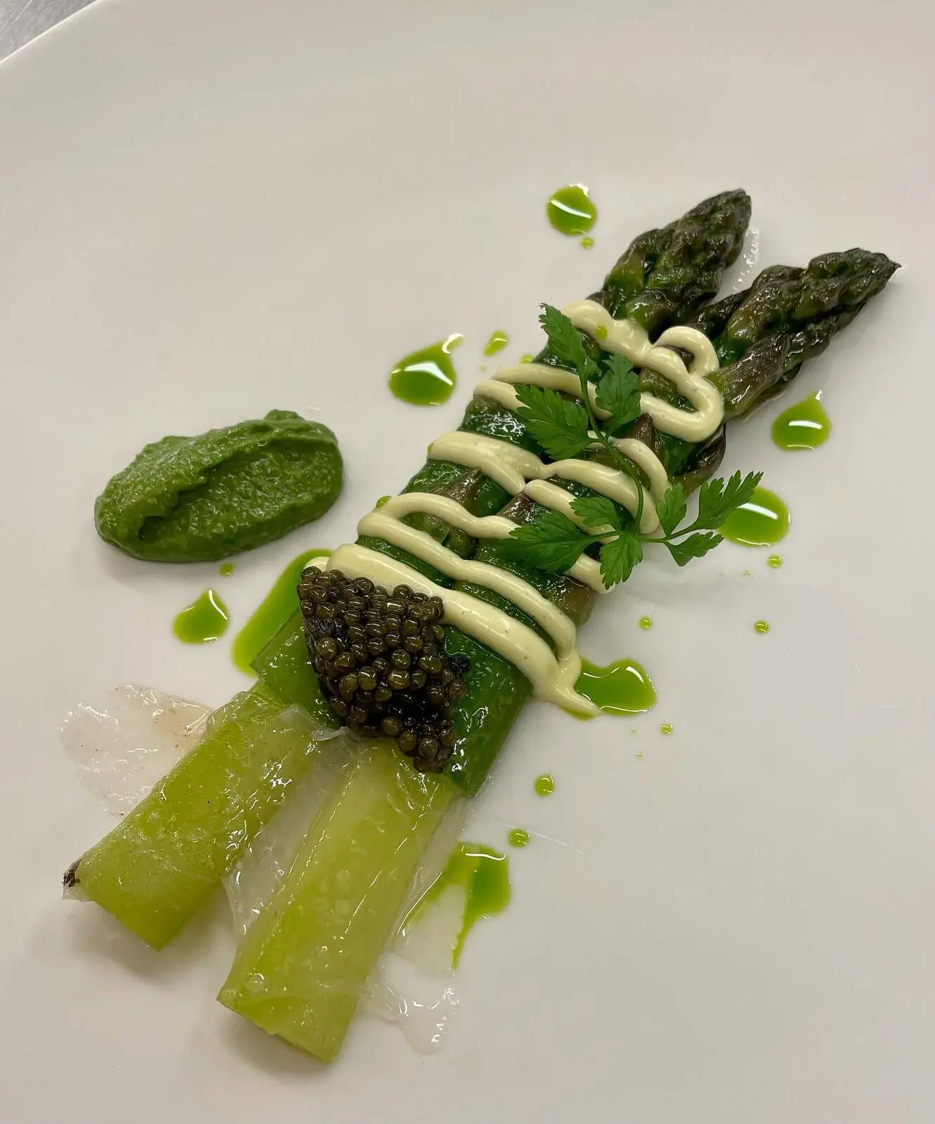 Asperges vertes et blanches nappées de sauce, caviar et pointes d’ail des ours.
