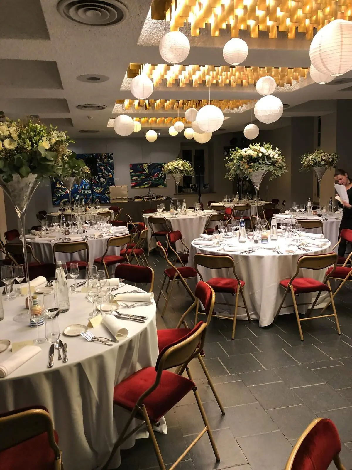 Grande salle du château dressée pour un banquet, lanternes suspendues.