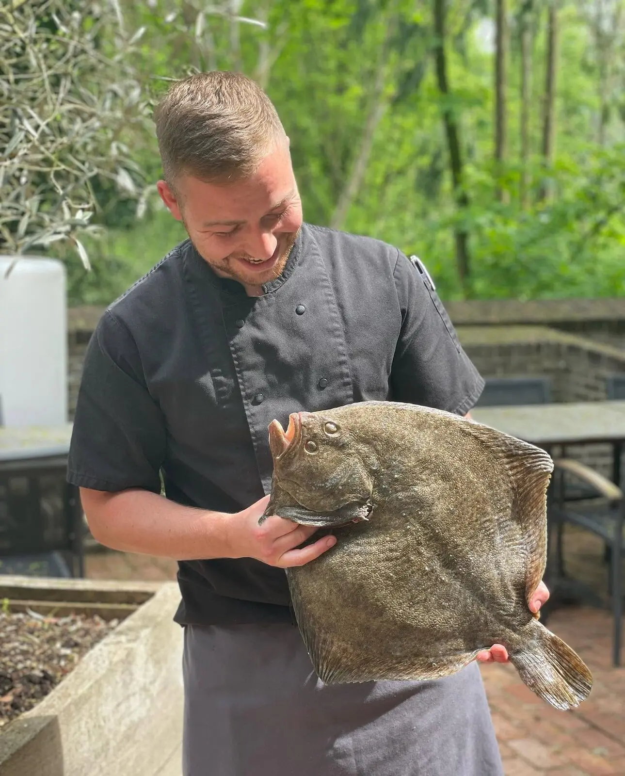Un cuisinier présente un turbot sauvage entier, devant le parc.
