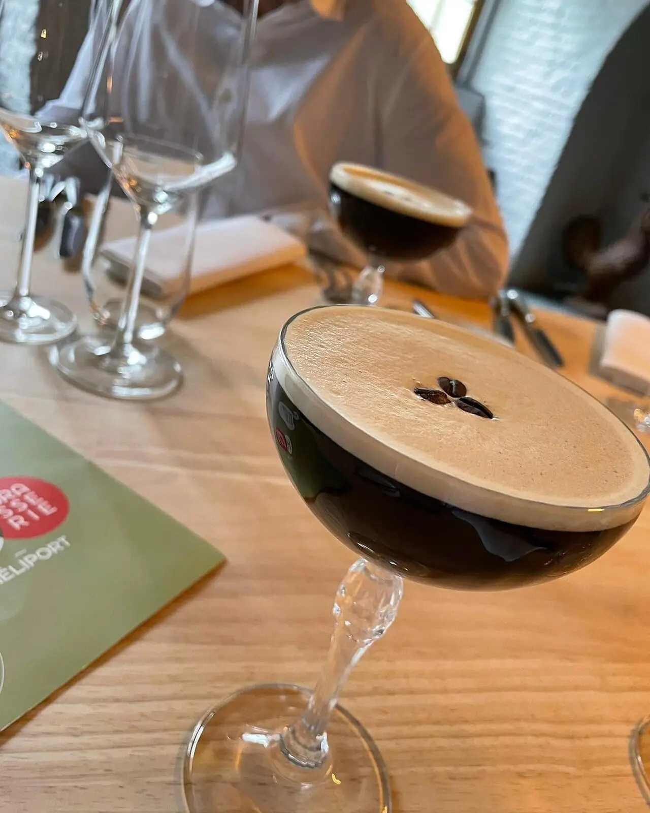 Expresso martini servi dans un verre à pied, mousse et grain de café.